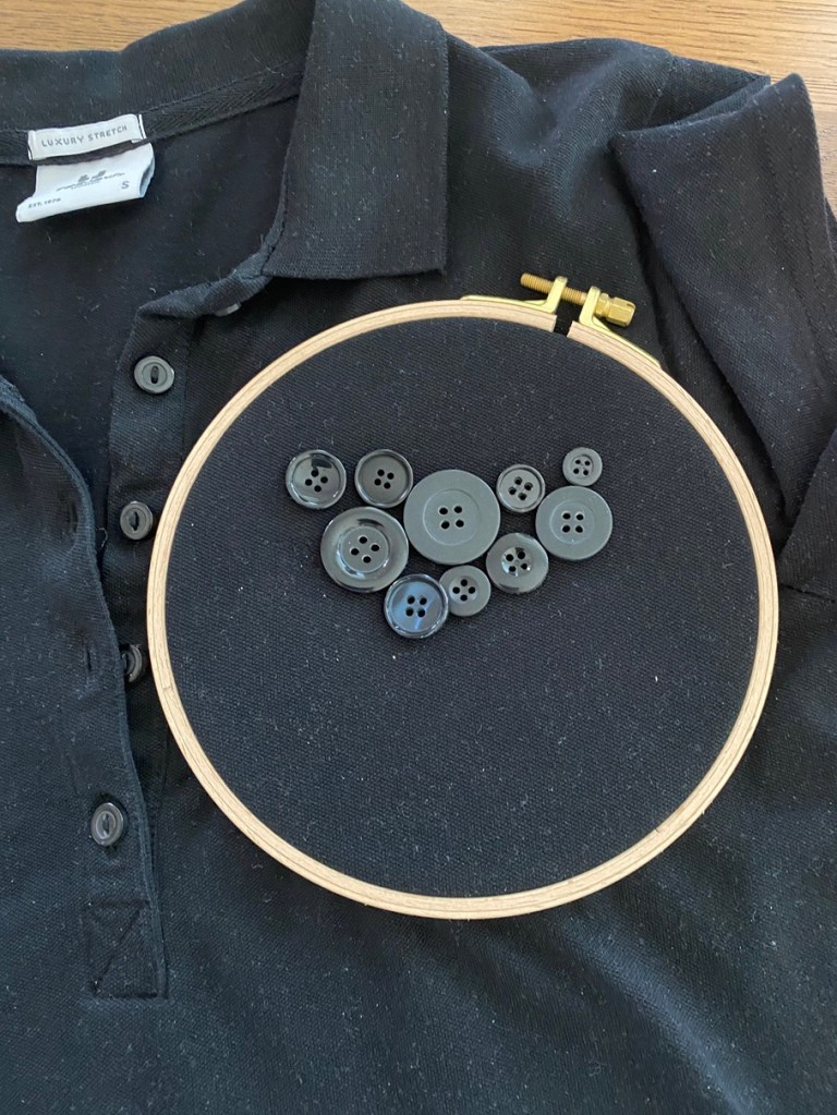 Kuvassa on musta pikeepaita, jossa on useampi musta nappi vierekkäin kuin peittämässä tahraa