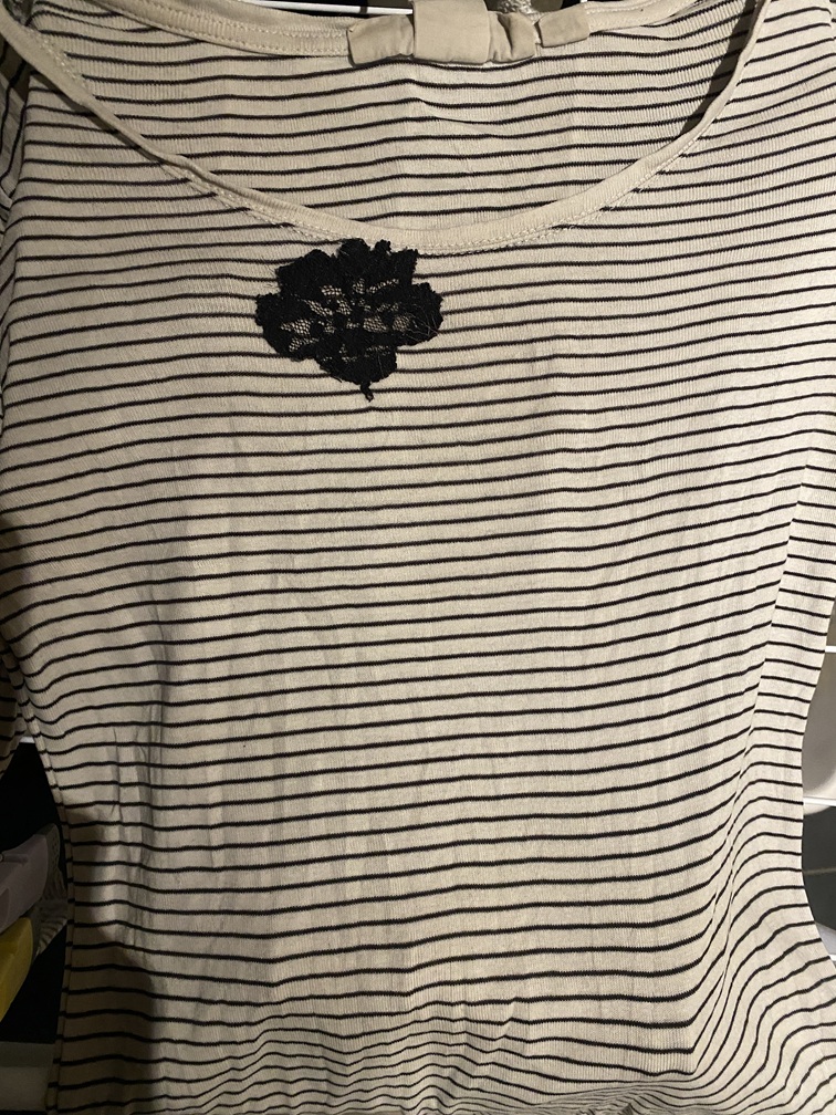 valko-mustaraidallinen paita, jonka kauluksen lähelle on ommeltu musta pitsikukka