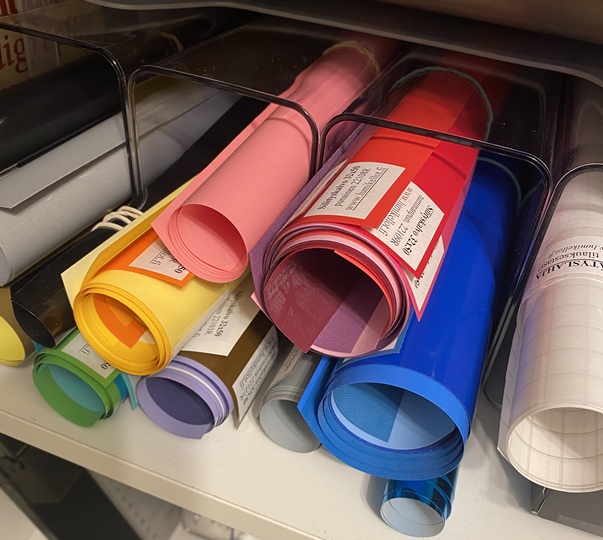 Värikkäitä vinyyliullia hyllyssä, mukana keltainen, vaaleanpunainen, punainen, sininen, vihreä ja violetti.