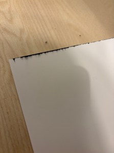 Lähikuva paperin kulmasta, jossa on mustaa jälkeä.