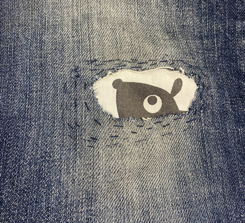 Reikä farkuissa, josta näkyy reiän läpi pieni ruskea eläinhahmo