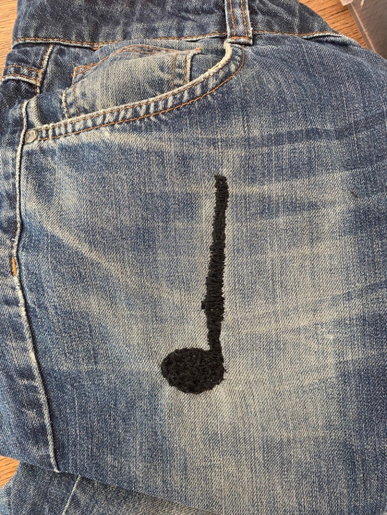 Siniset farkut, joissa on musta nuottikuvio kirjottu oikeassa lahkeessa.